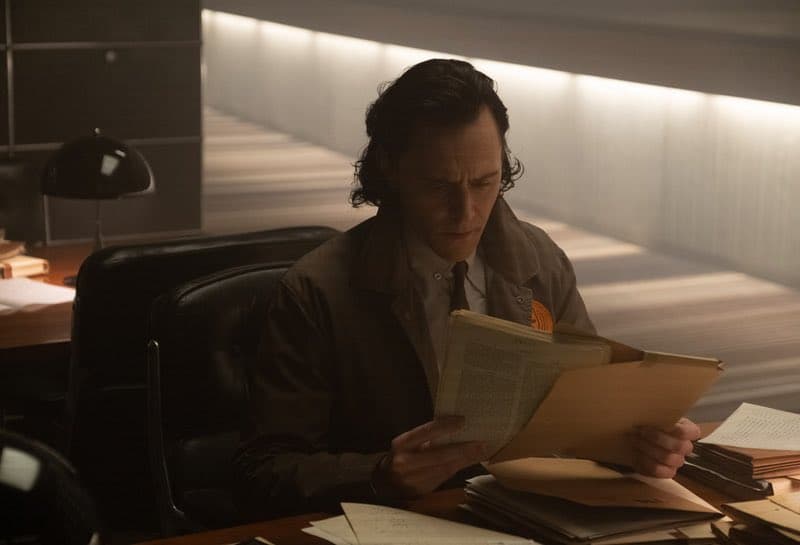 تام هیدلستون در حال خواندن فایل‌های سازمان TVA در قسمت دوم سریال Loki